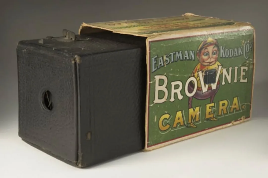 Who invented a small box camera that made it cheaper to take pictures?