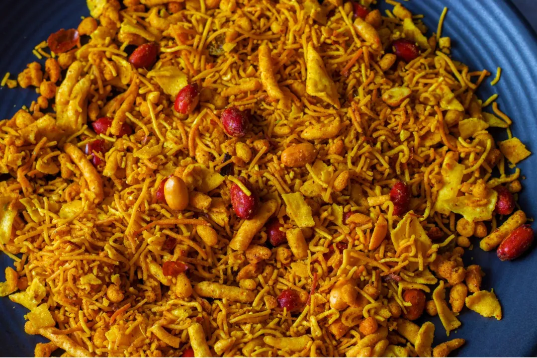 For a person aiming for a 2,000-calorie diet, what fraction of their daily energy budget does consuming the full 100g serving of Bombay mix account for?